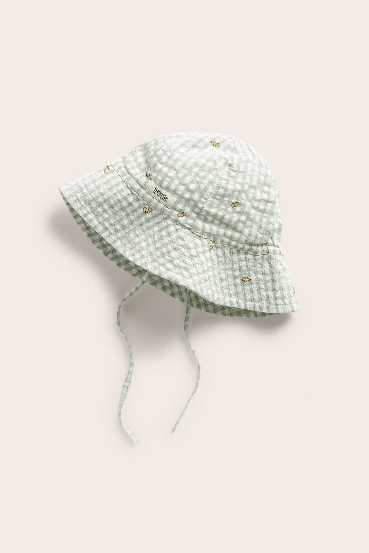 Top view of a kid's light green checked cotton sun hat with tie-straps and embroidered bees.