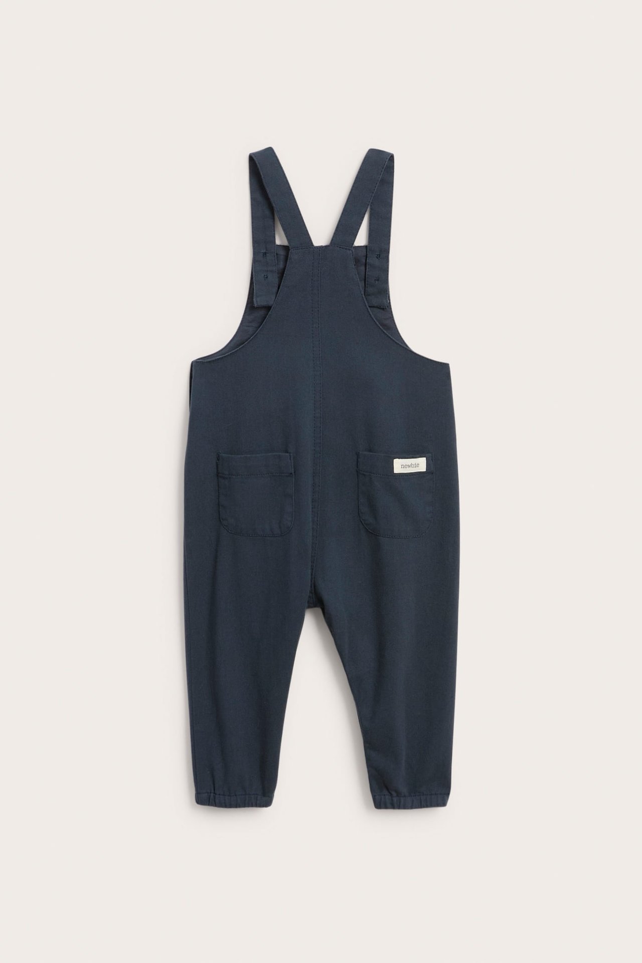 Back view of dark blue baby overalls with buttoned straps and back pockets.