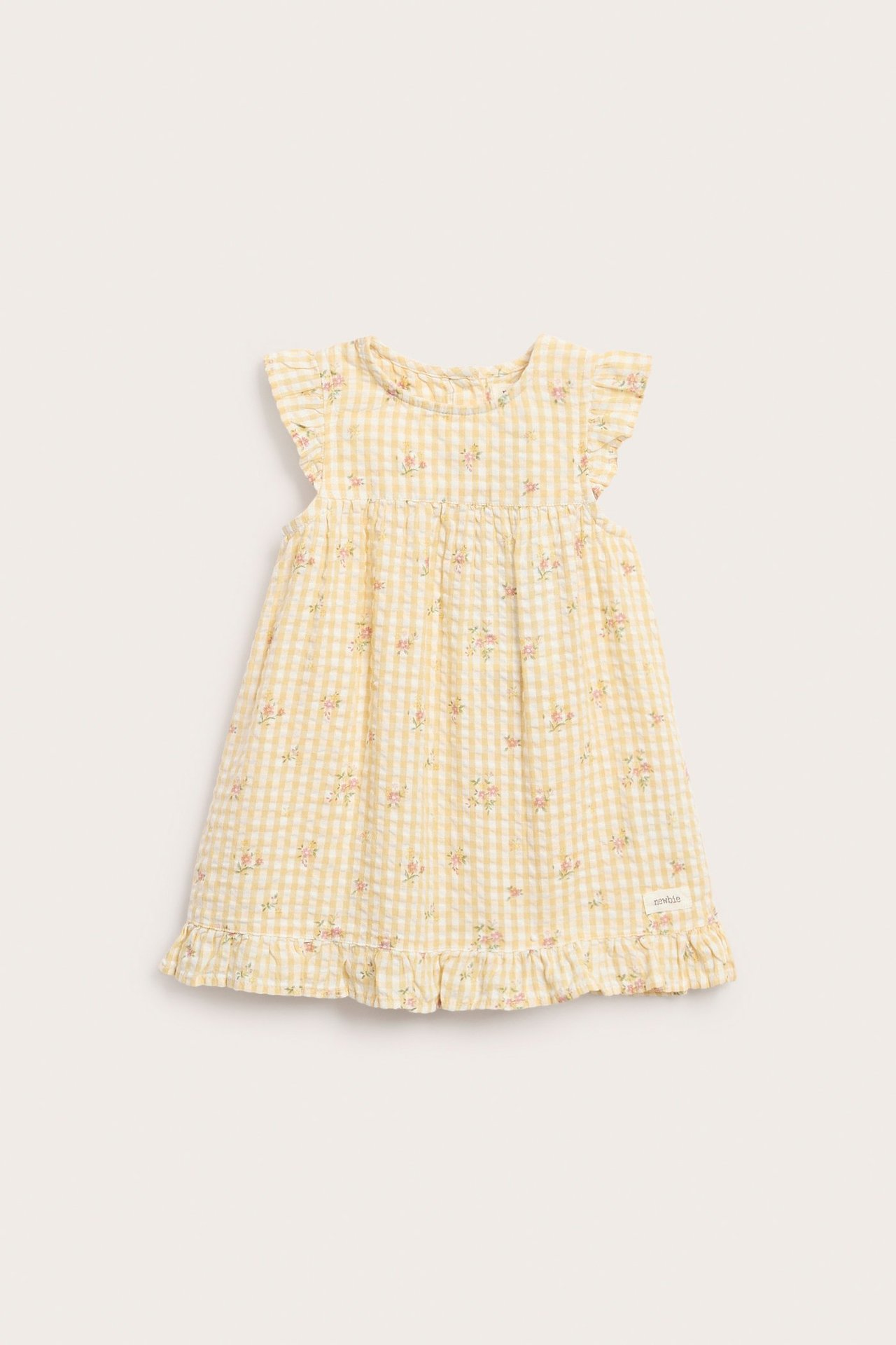 Vorderansicht eines gelben Kinderkleides mit Vichy-Karo, Blumenmuster, Rüschenschultern und Rüschensaum.