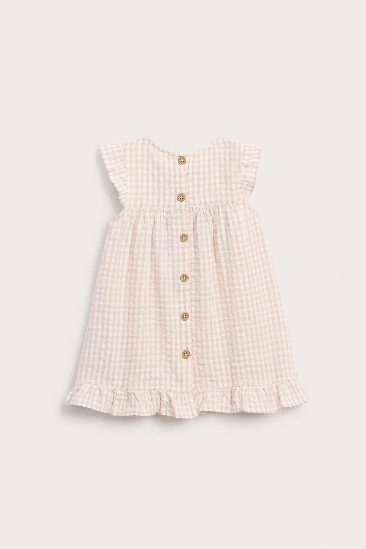 Vorderansicht eines hellrosa-weiß karierten Baumwoll-Babykleides mit Rüschenärmeln, Saum und Knöpfen hinten.