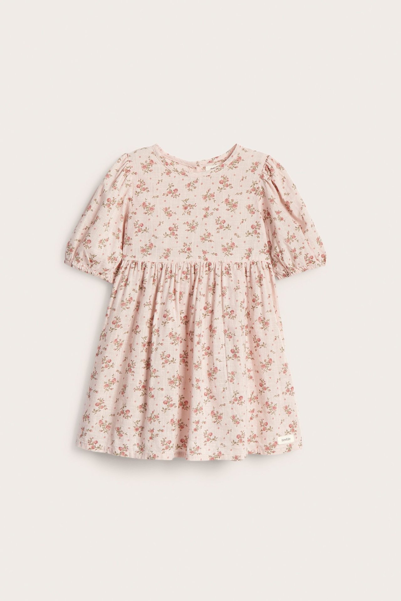 Front view of a light pink kid's dress with puff sleeves, elastic cuffs, and a floral pattern.