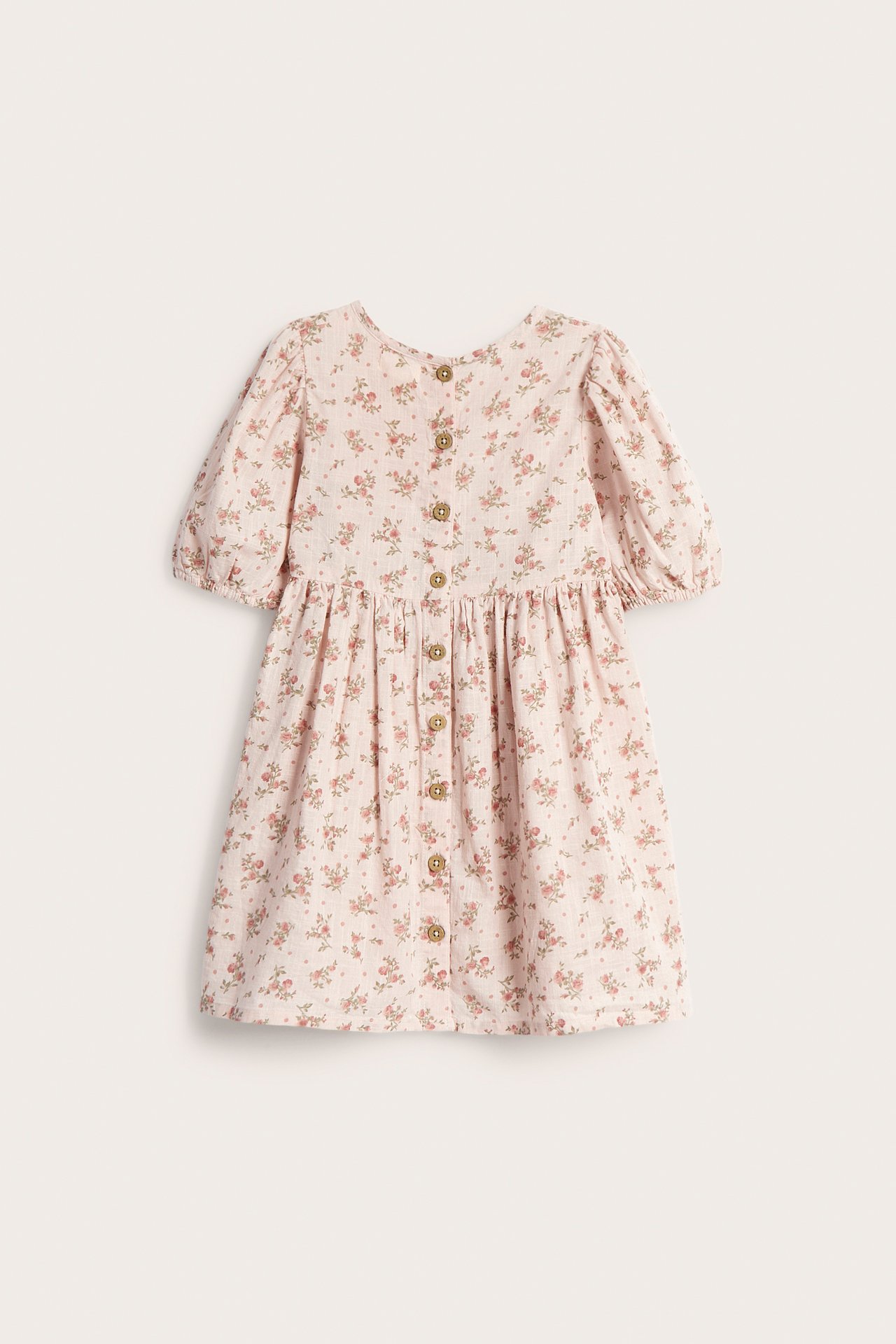 Back view of a kid's light pink floral dress with short puff sleeves and button fastening.