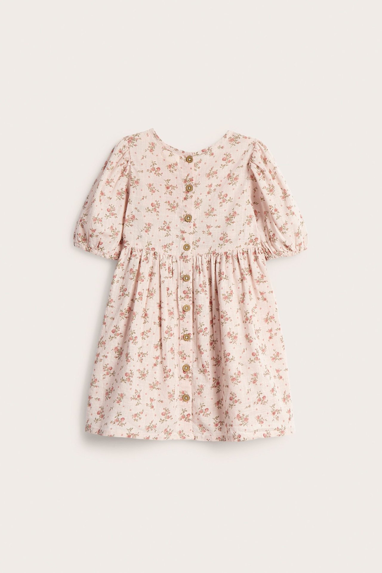 Back view of a kid's light pink floral dress with short puff sleeves and button fastening.