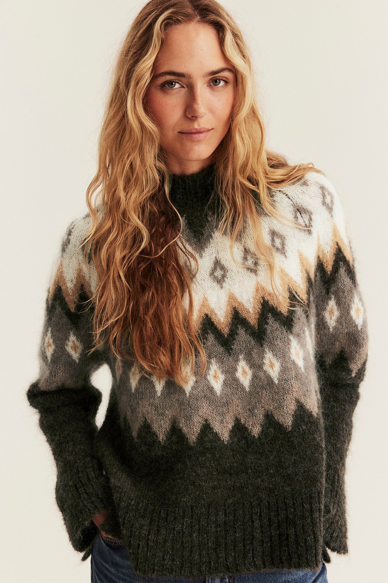 Vorderansicht einer erwachsenen Frau in gemustertem Strickpullover und blauen Jeans.