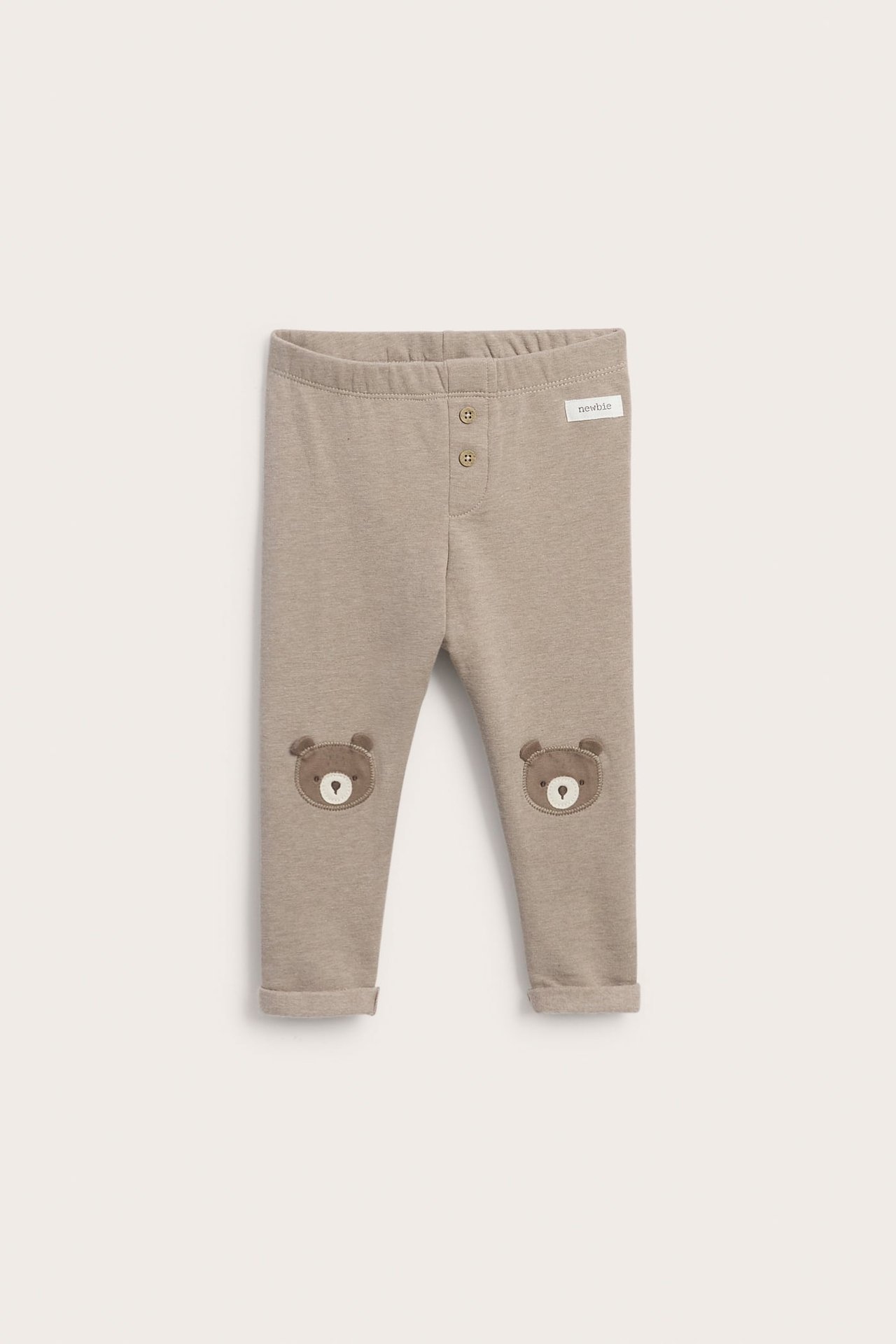 Vorderansicht von hellbraunen Baby-Leggings mit zwei Knöpfen vorne und Bären-Knieapplikationen.