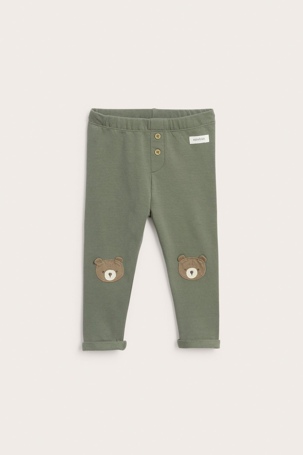 Front view: Baby's green leggings with button details and bear knee patches.
