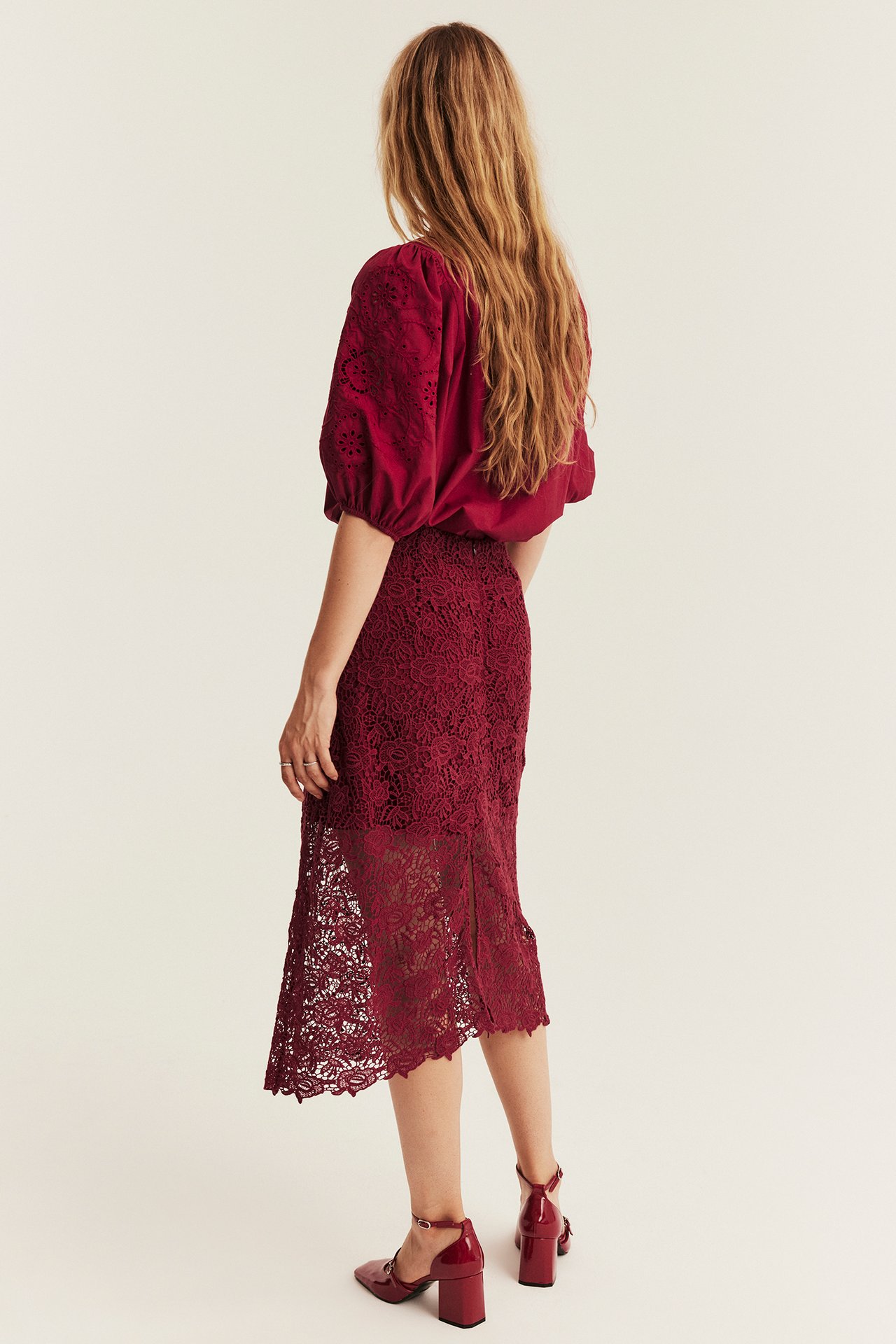 Women's back view: burgundy lace midi skirt, matching embroidered blouse, and block-heel shoes.