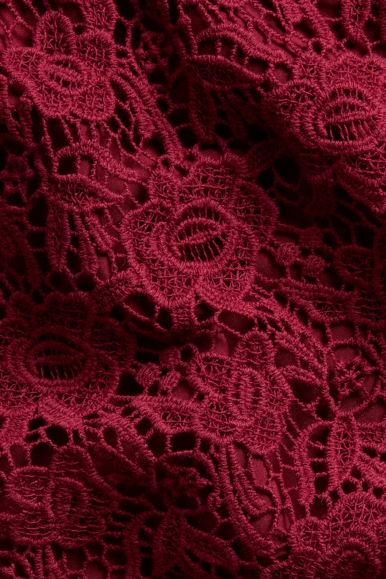 Close-up of a dark red floral lace fabric with intricate details.