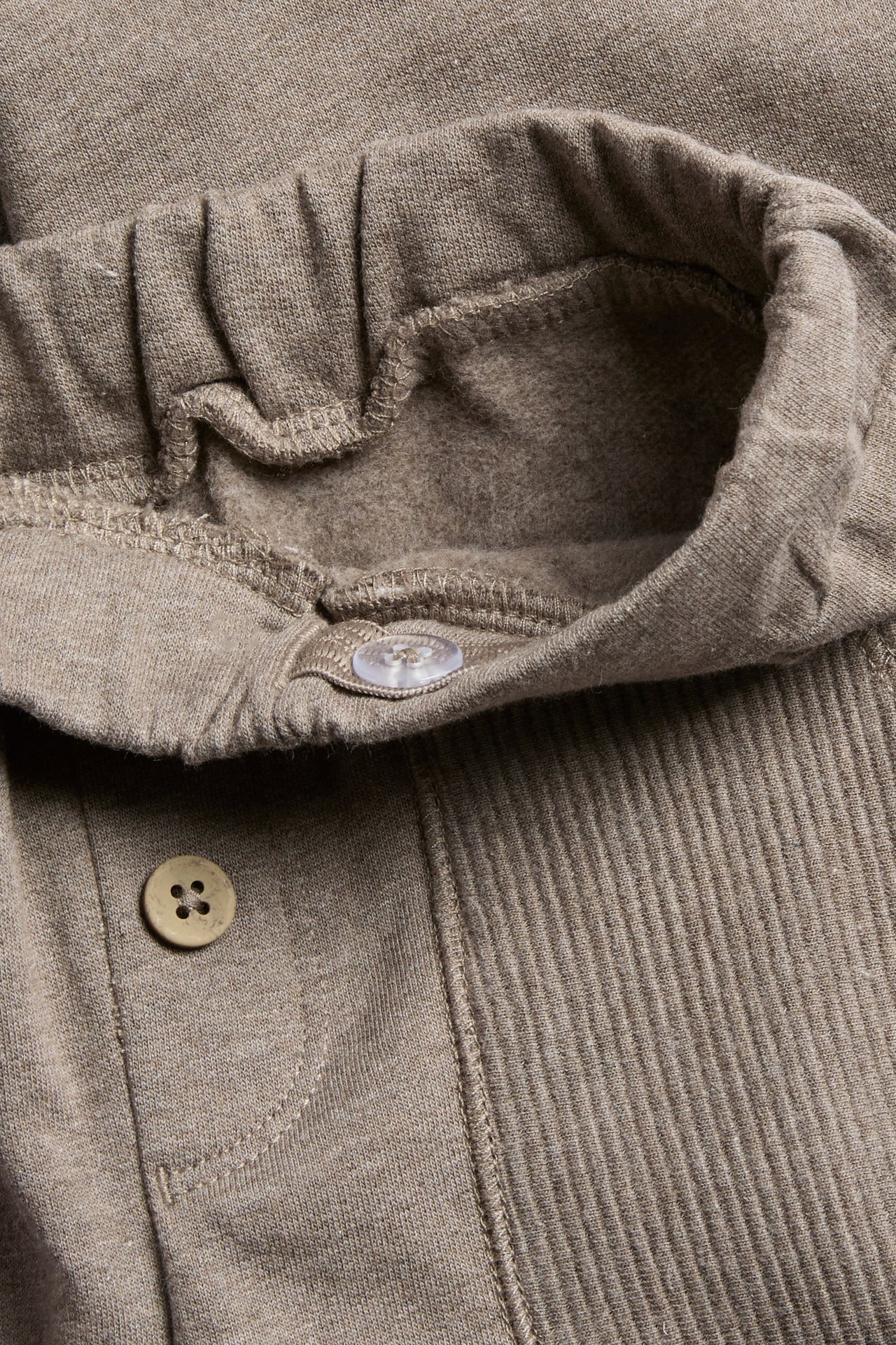 Nahaufnahme von braunen Loungewear-Hosen mit elastischem Bund und sichtbaren Knöpfen.