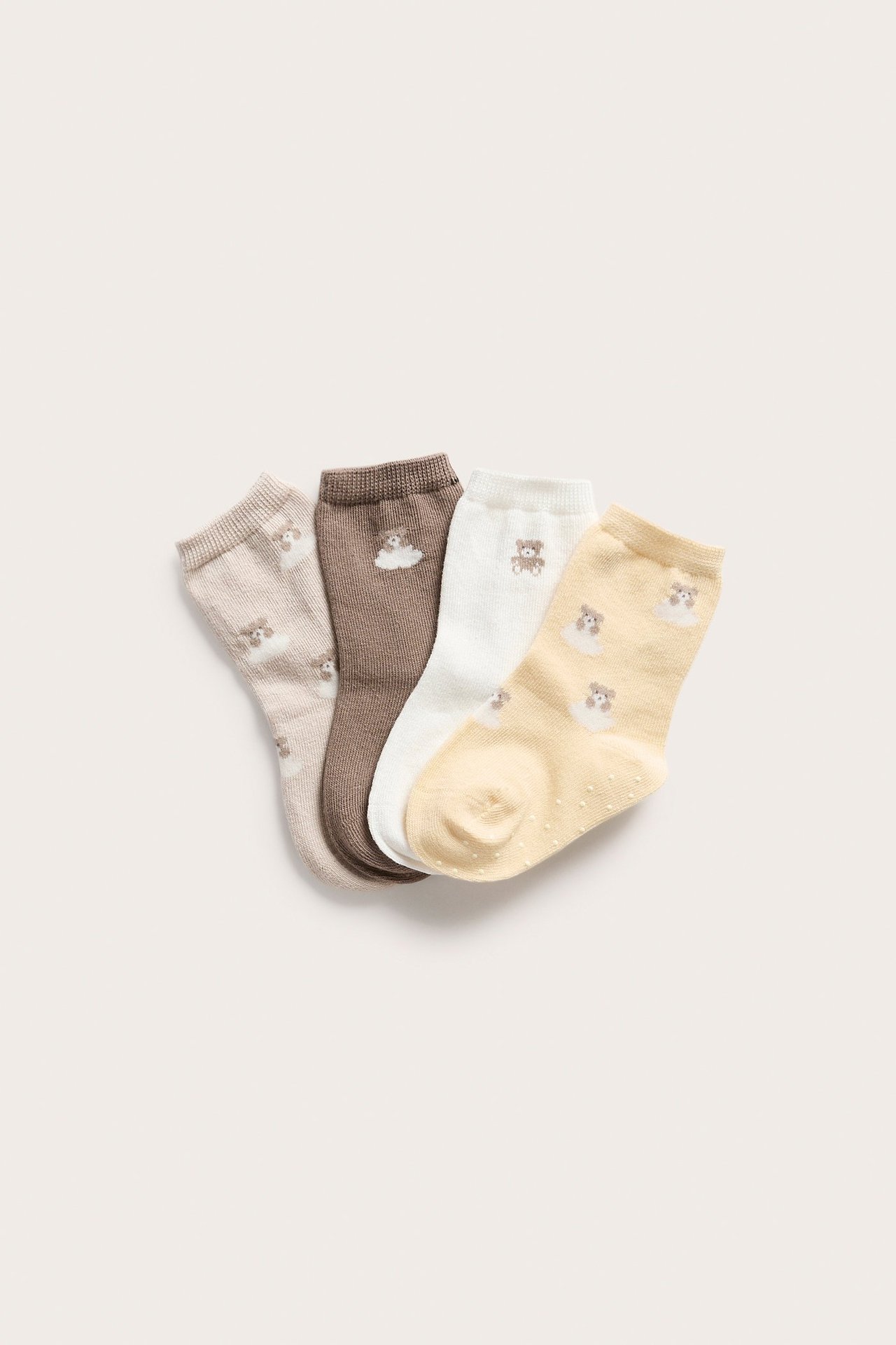 Four baby socks: beige, brown, white, yellow. Features teddy bears, clouds, and anti-slip dots.