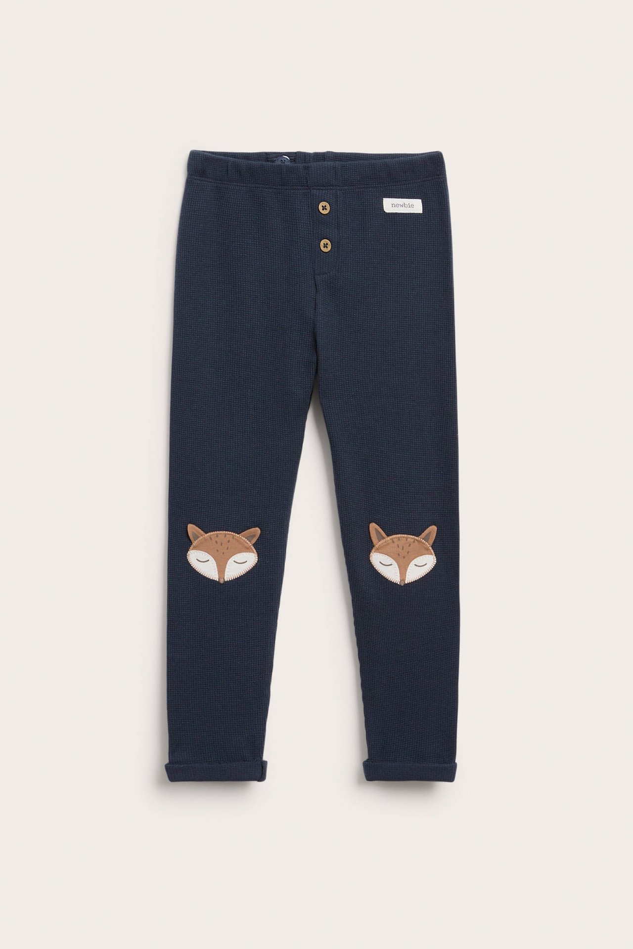 Front view of dark blue waffle knit baby pants with fox knee patches and front buttons.