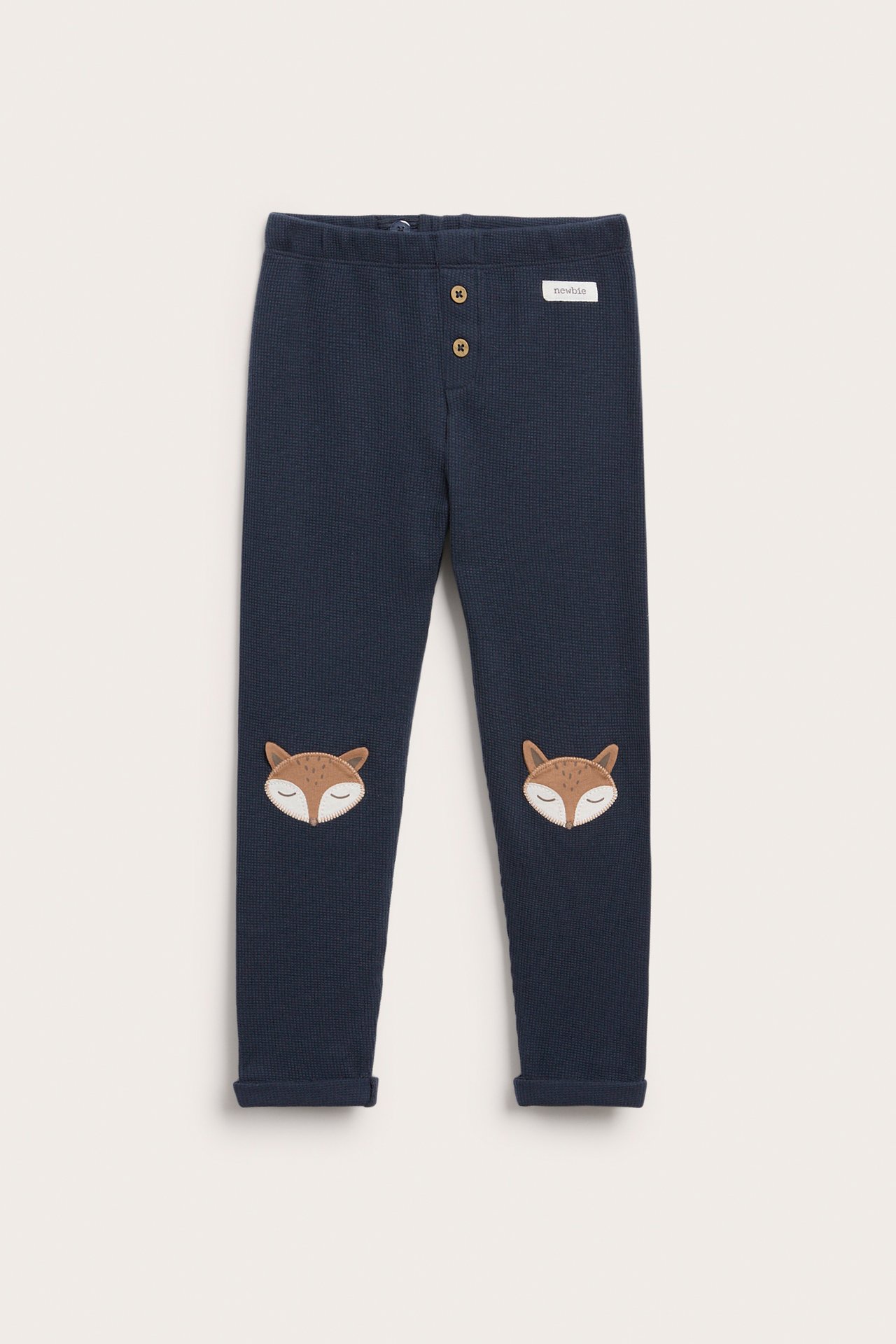 Vorderansicht dunkelblauer Waffelstrick-Babyhose mit Fuchsknie-Applikationen und Knöpfen vorne.