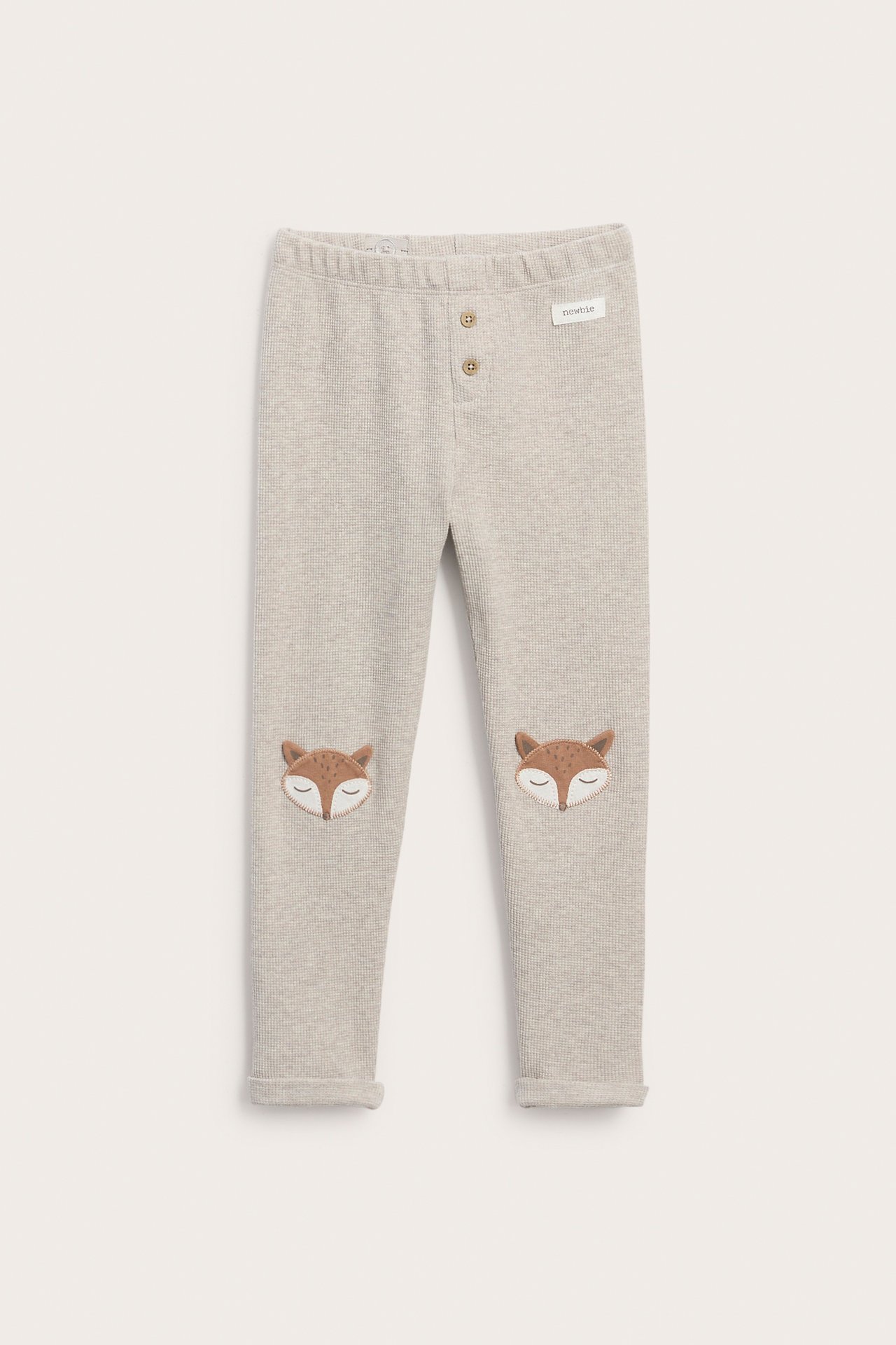 Vorderansicht: Hellgraue gerippte Kinderleggings mit zwei Knöpfen vorne und Fuchsköpfen an den Knien.