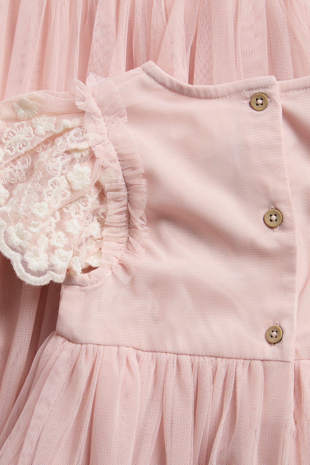 Nahaufnahme Rückenansicht eines rosa Babykleids mit Spitzärmeln und braunen Knöpfen.