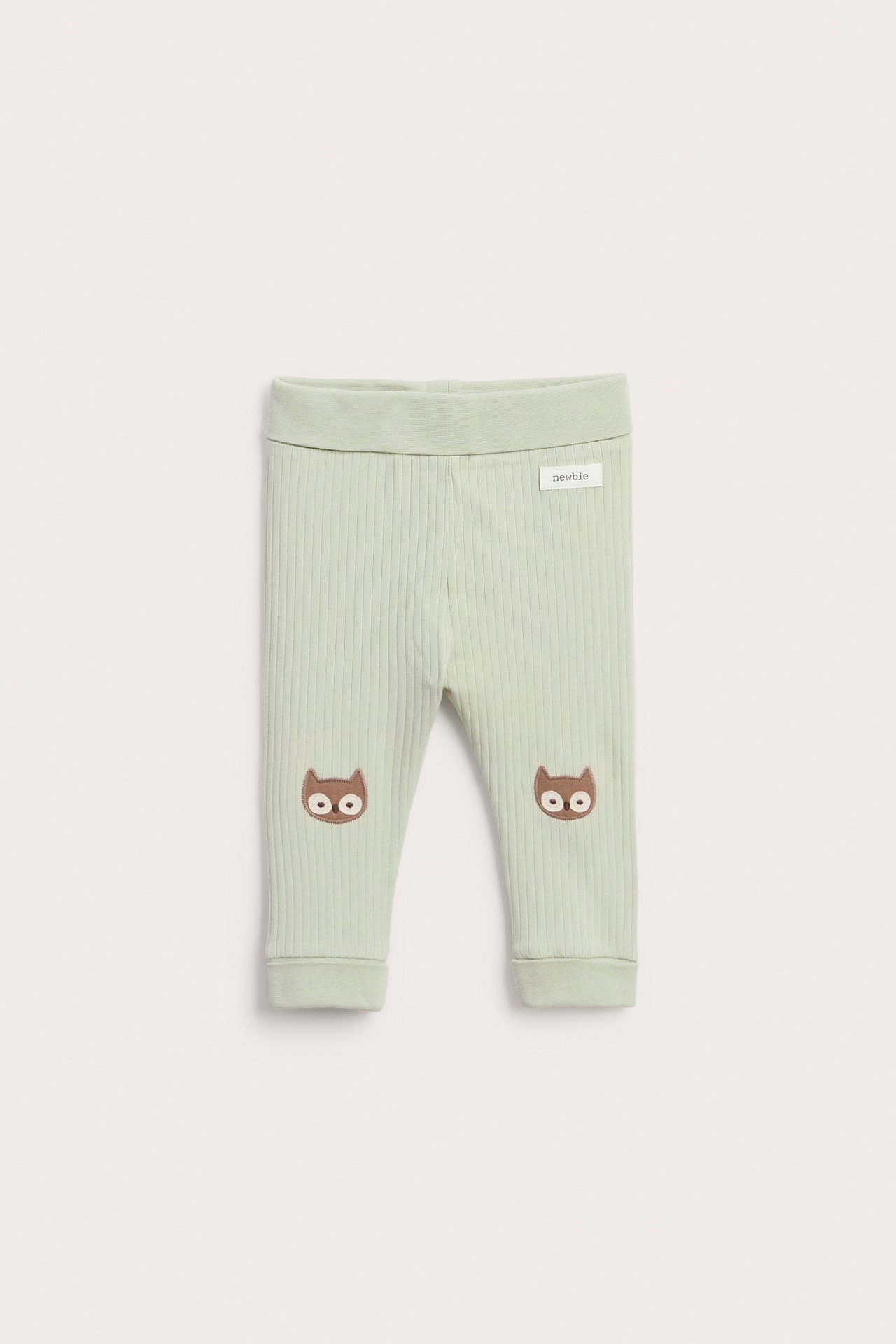 Vorderansicht hellgrüner gerippter Baby-Leggings mit braunen Eulengesichtern auf den Knien.