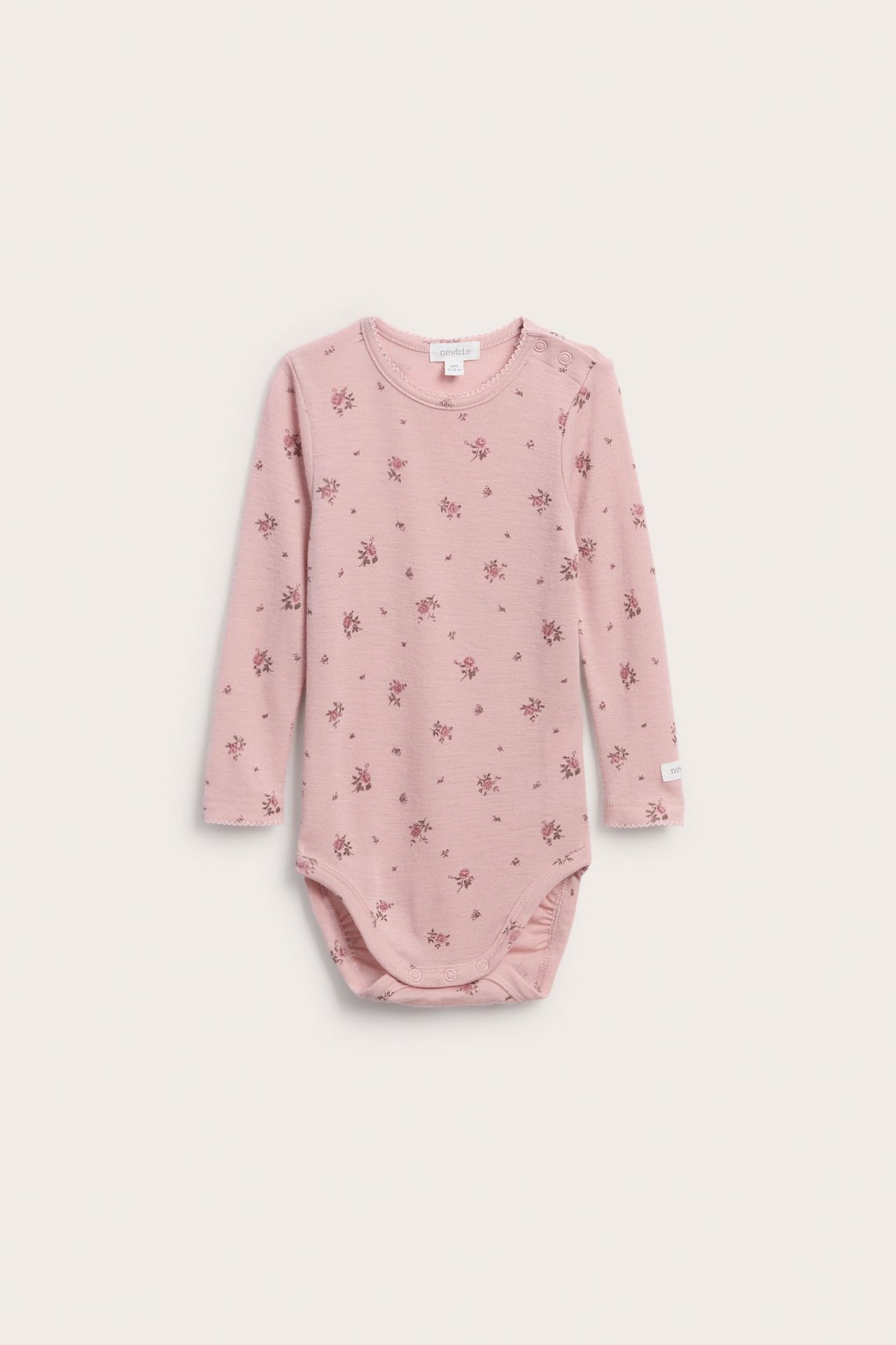 Front view of a baby pink long-sleeved floral print bodysuit with snap buttons.