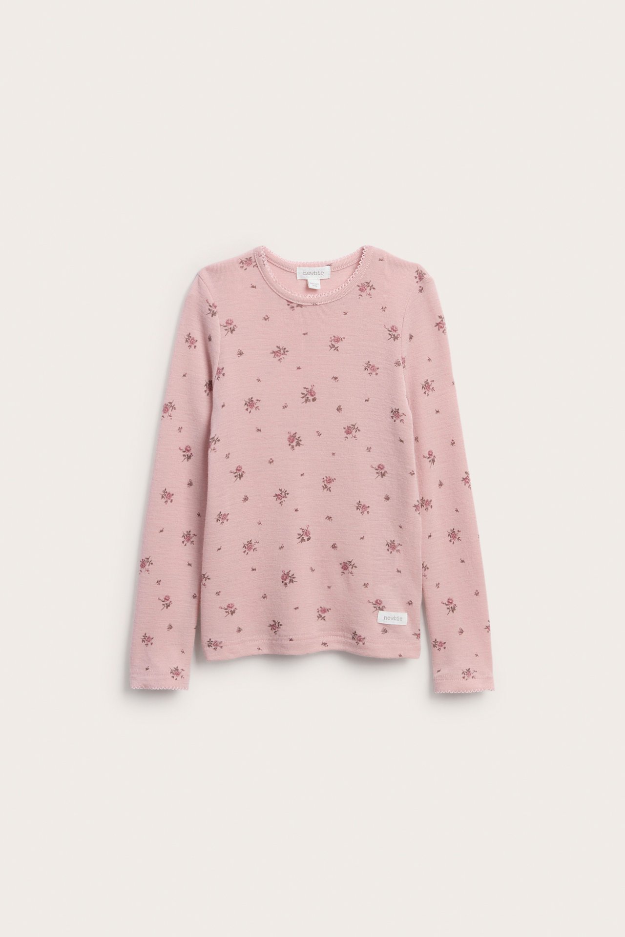 Vorderansicht eines pinkfarbenen Kinder-Langarmshirts mit Blumenmuster und Wellenkante.