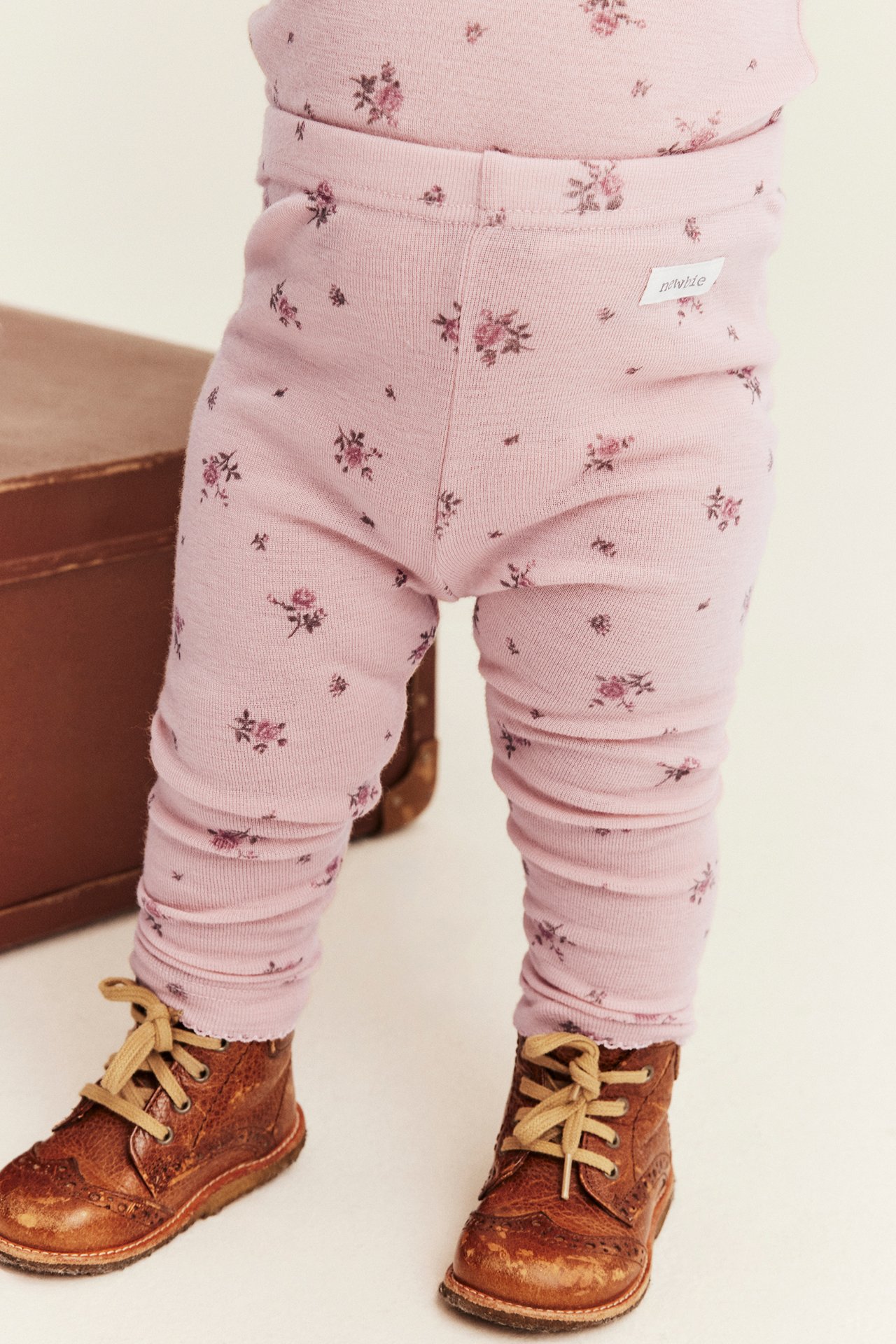 Front view of baby wearing pink floral leggings and brown laced shoes.