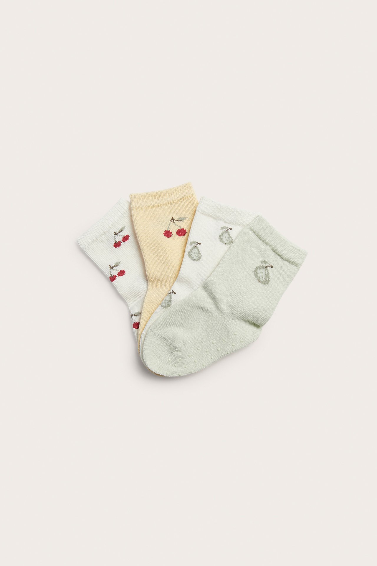 Top-down view of four patterned kids' socks: off-white cherry, light yellow cherry, off-white pear, and light green anti-slip.