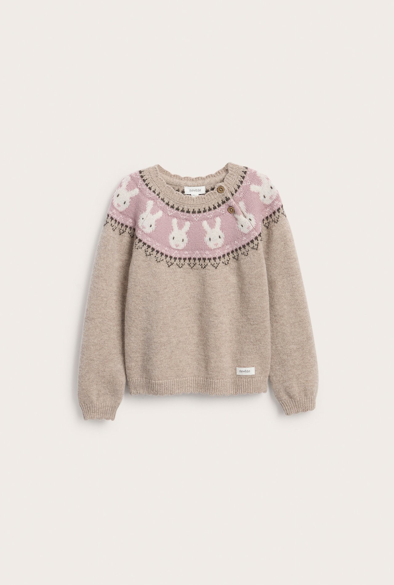 Vorderansicht eines beigen Kinderpullovers mit rosa Passe, weißem Hasenmuster und zwei Knöpfen.