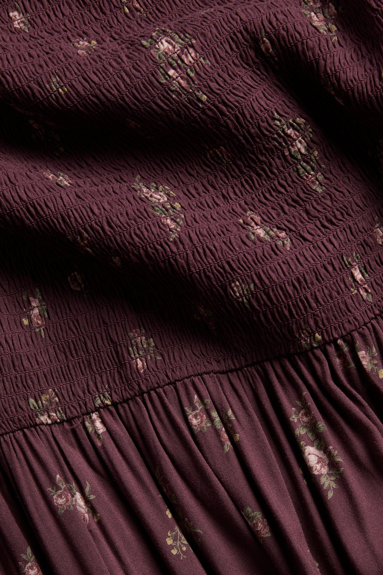 Close-up of a dark plum shirred floral fabric with gathers.