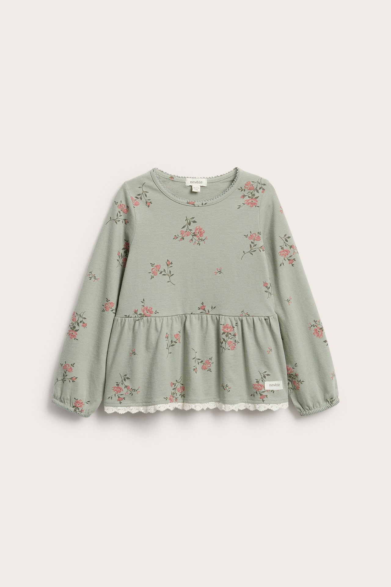 Vorderansicht eines grünen geblümten Langarm-Peplum-Tops aus Baumwolle für Kinder mit weißer Spitze.