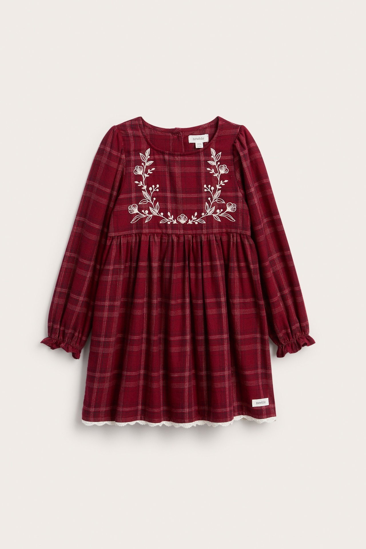 Front view of a kid's red plaid long-sleeved dress with white floral embroidery and lace trim.