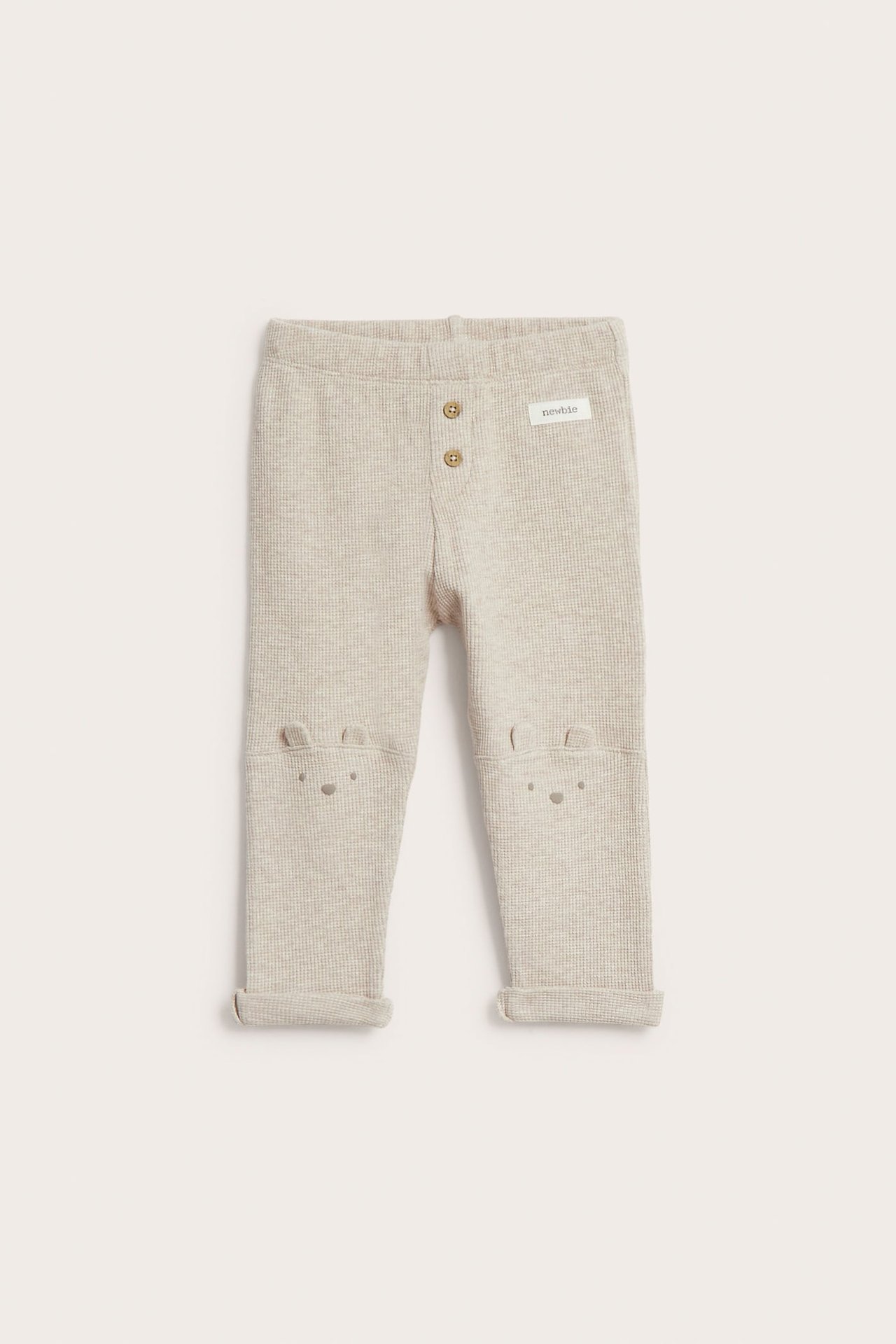 Vorderansicht, beige melierte Waffel-Leggings für Babys mit Zierknöpfen und Bärenohren-Applikationen.