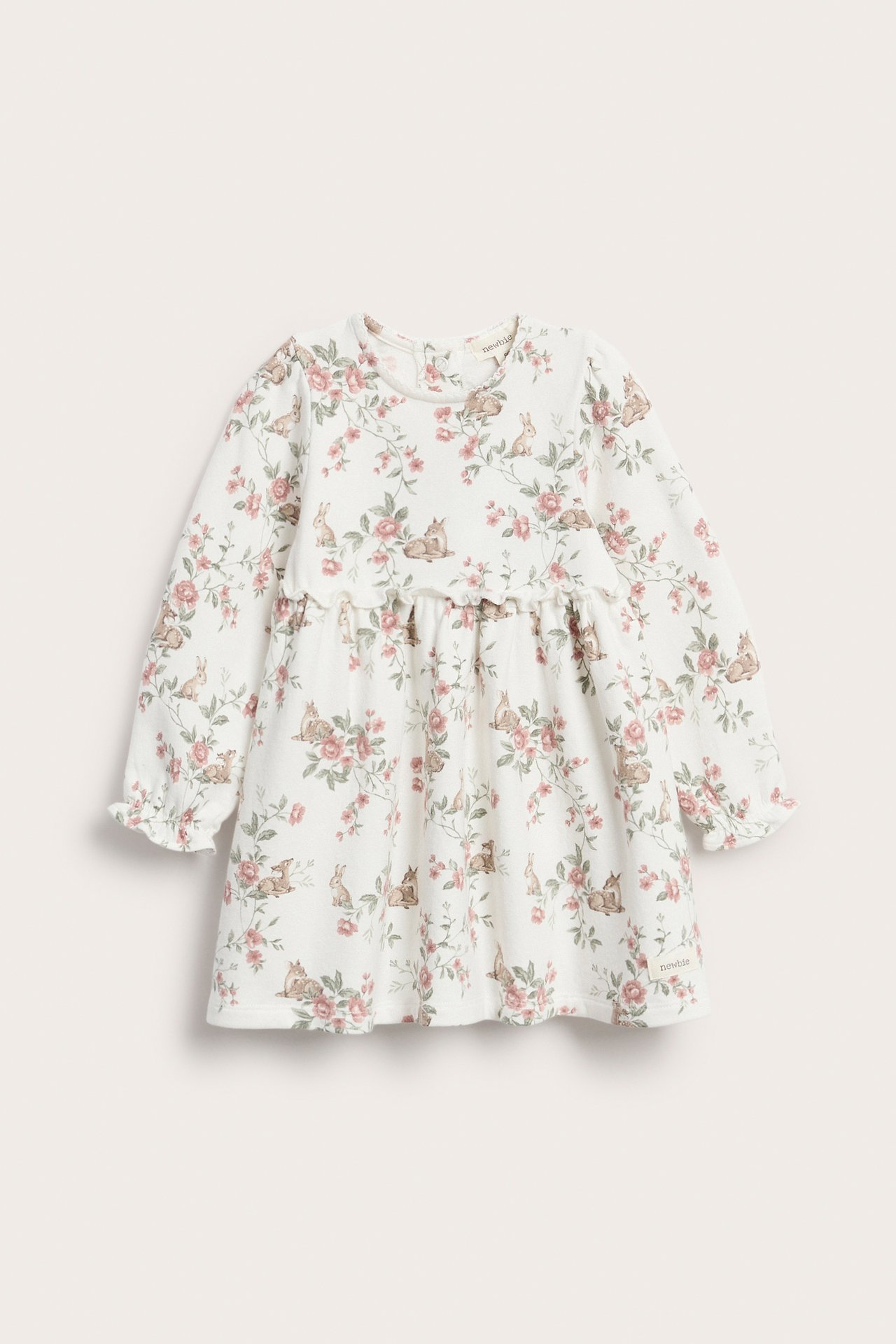 Front view of an off-white jersey baby dress with pink floral and deer patterns, long sleeves, and ruffled cuffs.