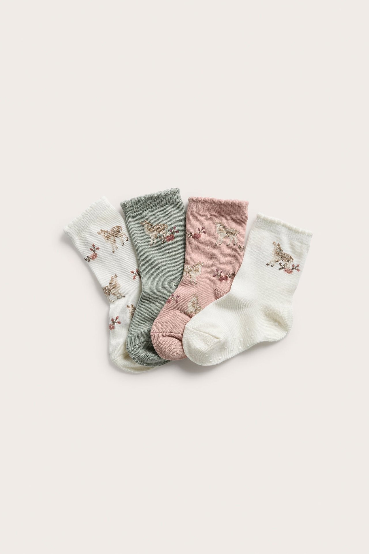 Vier Paar Babysocken: gebrochenes Weiß, Salbeigrün und Rosa, alle mit Reh- und Blumenmustern.