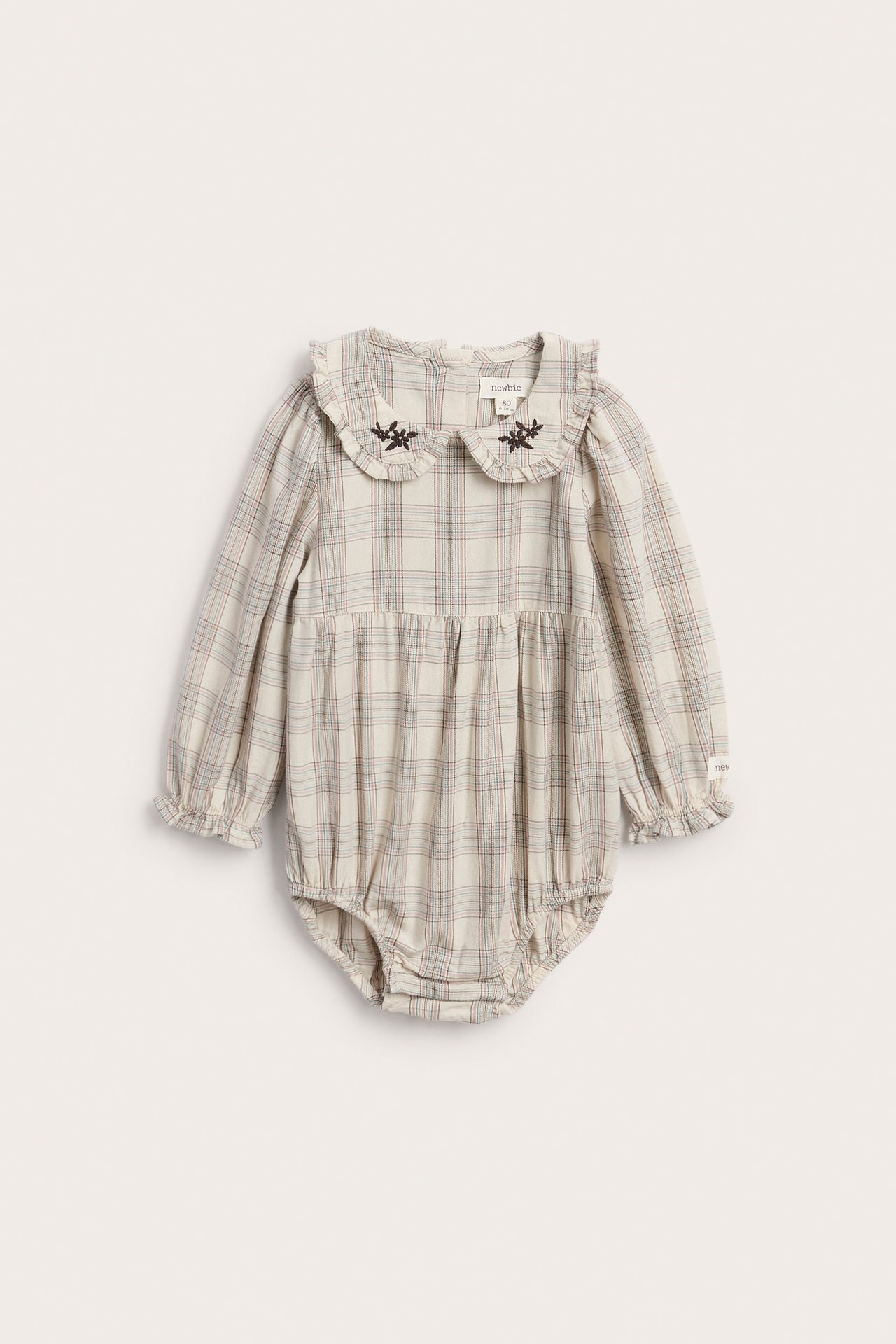Front view of a baby's cream plaid long-sleeved romper with an embroidered ruffled collar.