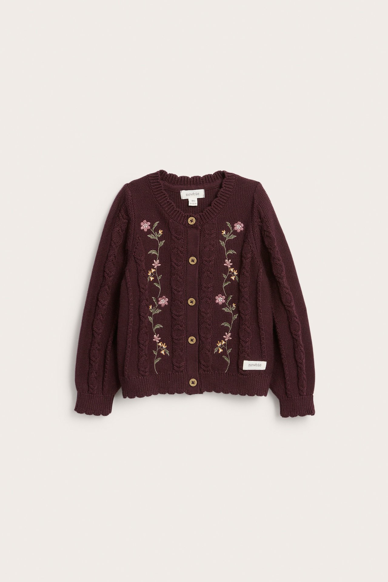 Vorderansicht einer dunkelroten Strickjacke für Babys mit Blumenstickerei und Zopfmuster.