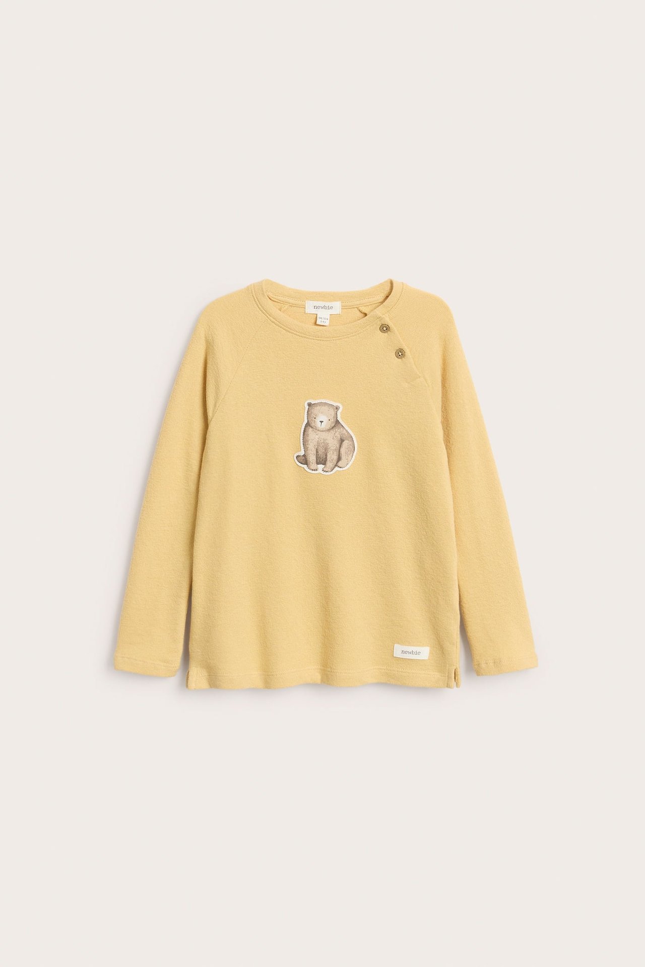 Front view of a kid's yellow long-sleeved top with a bear print and two shoulder buttons.