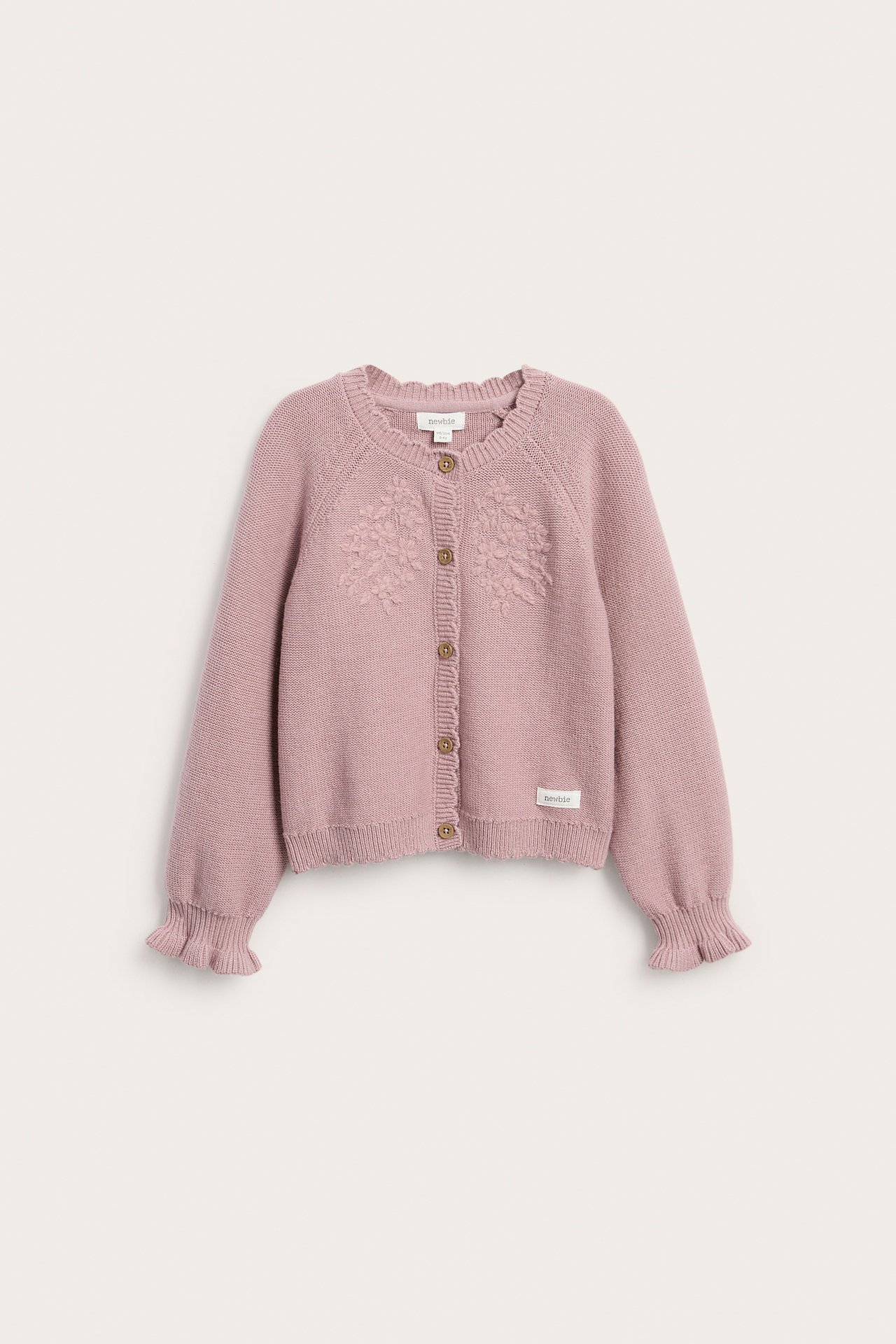 Vorderansicht einer rosa Strickjacke für Kinder mit Blumenstickerei, Knopfverschluss und Rüschenärmeln.
