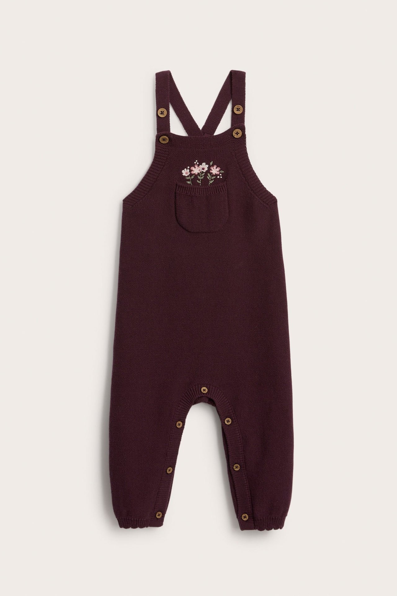 Vorderansicht eines Baby Strick-Overalls in Burgund mit Blumenstickerei und Druckknöpfen.