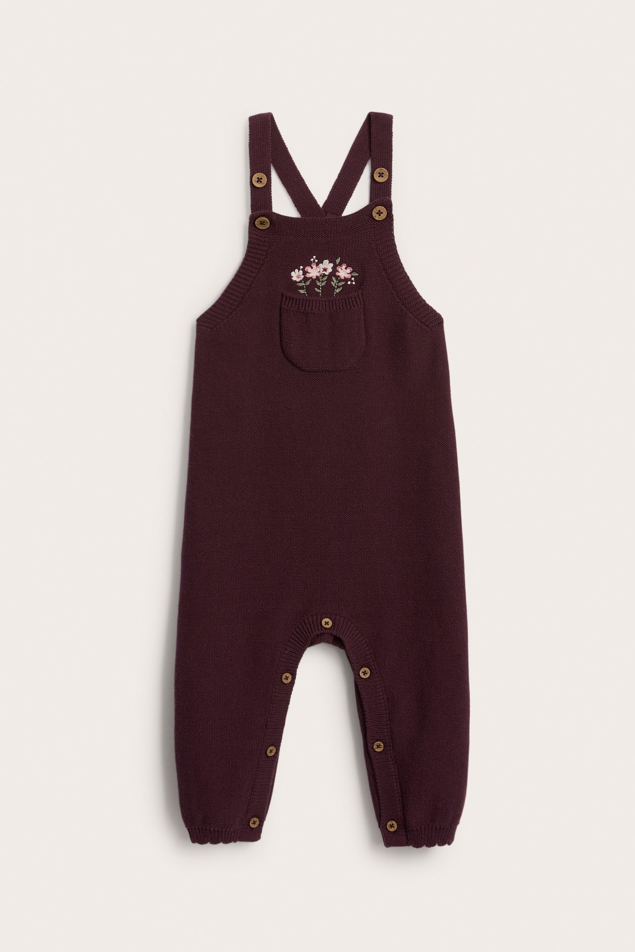 Vorderansicht eines Baby Strick-Overalls in Burgund mit Blumenstickerei und Druckknöpfen.