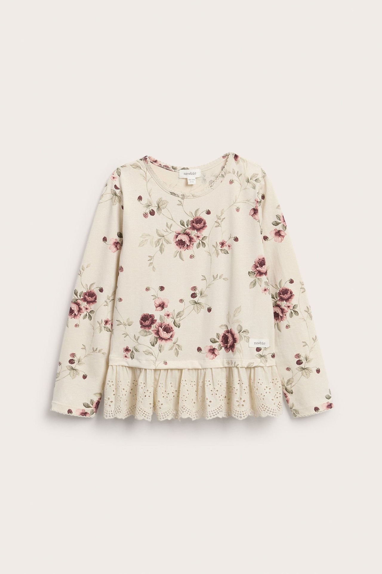 Vorderansicht eines creme Kinder-Langarmshirts mit Blumenmuster und Rüschenspitzenbesatz.