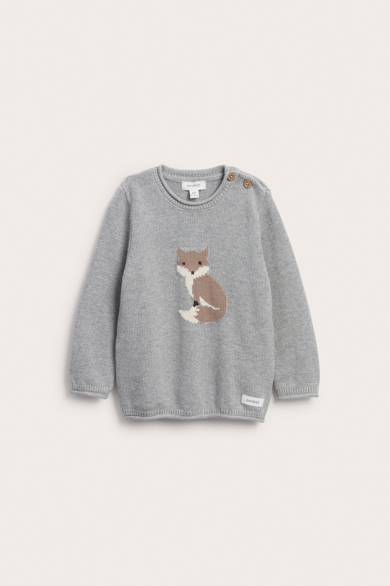 Vorderansicht eines grauen Babystrickpullovers mit Fuchsmotiv, Schulterknöpfen und kleinem Etikett.
