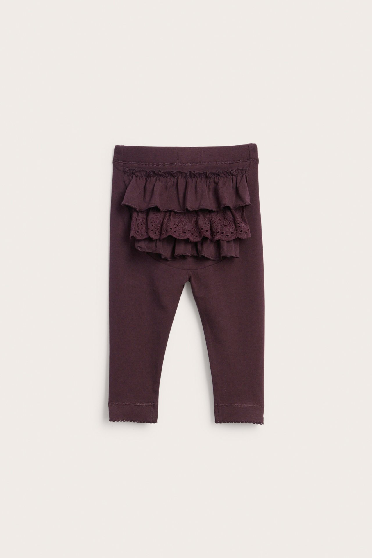 Back view of dark purple baby leggings with tiered ruffles and eyelet lace detail on the back, scalloped cuffs.