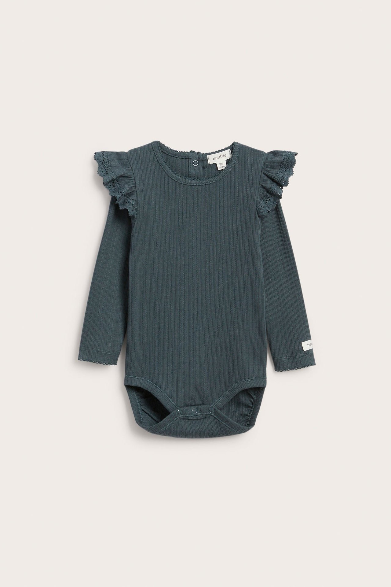 Vorderansicht eines petrolblauen gerippten Babybodys mit langen Ärmeln, Rüschenschultern, Druckknöpfen im Schritt.