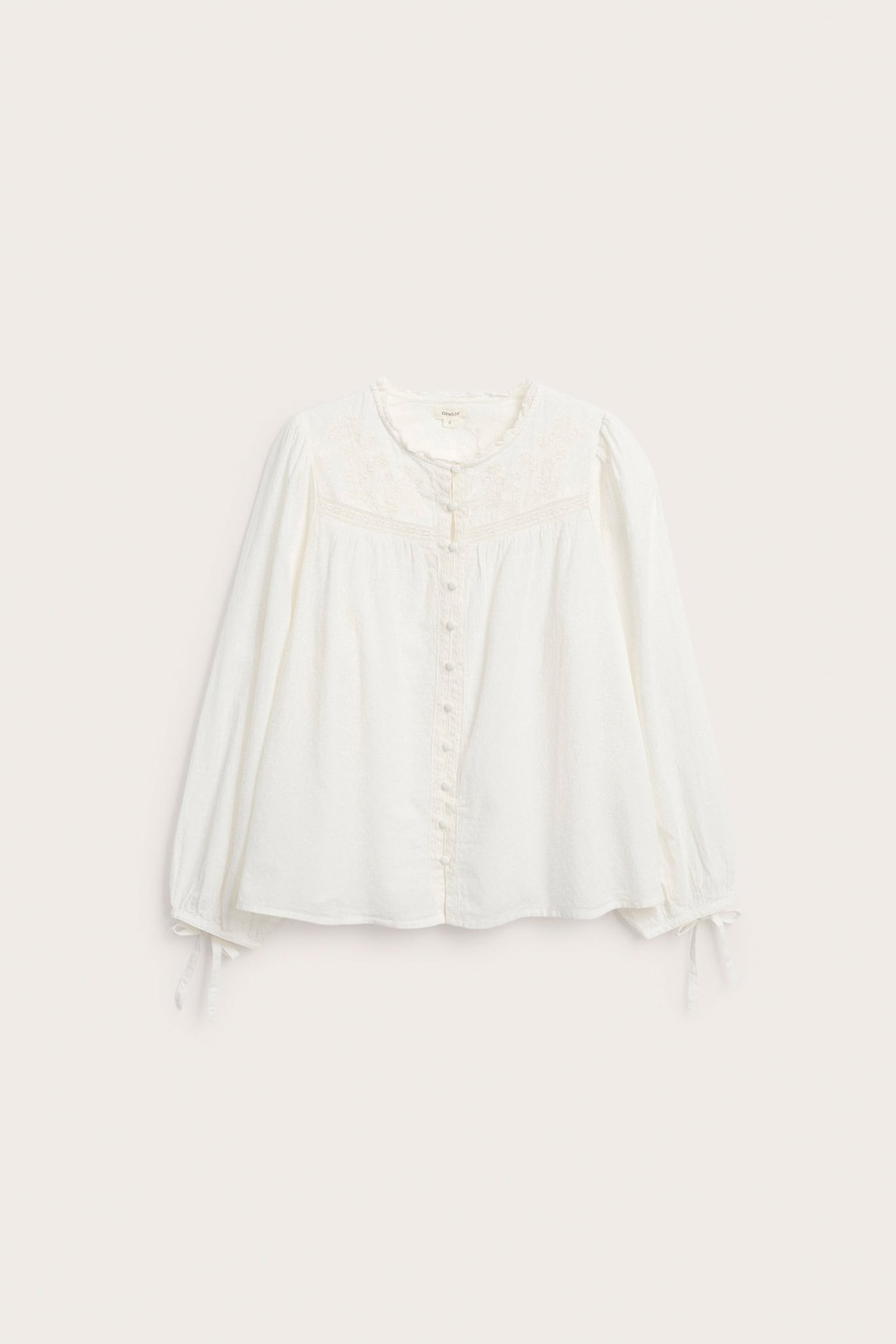 Front view of a white long-sleeved embroidered blouse with button front and cuff ties.