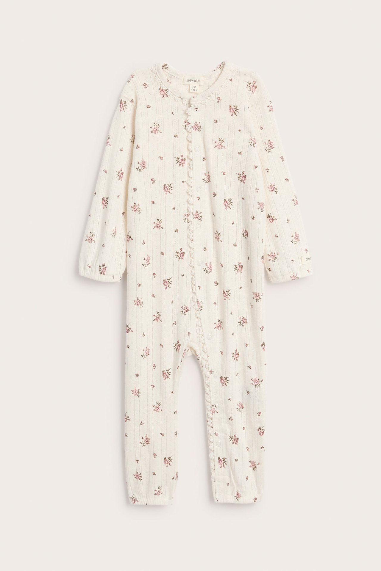 Vorderansicht eines babycremefarbenen gerippten Stramplers mit rosa Blumenmuster und Druckknöpfen.