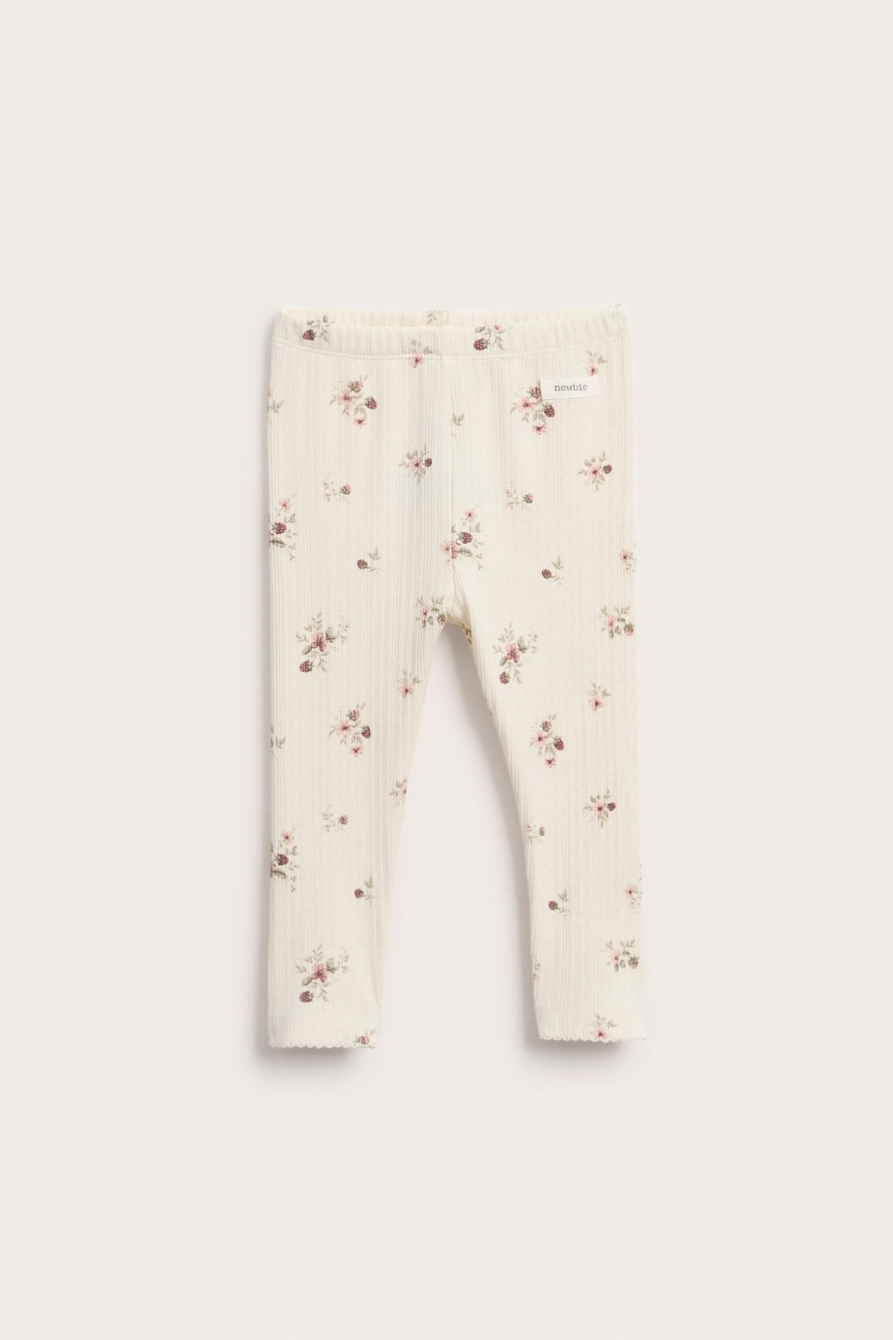 Front view of ribbed cream baby leggings with small pink floral print and scalloped hems.