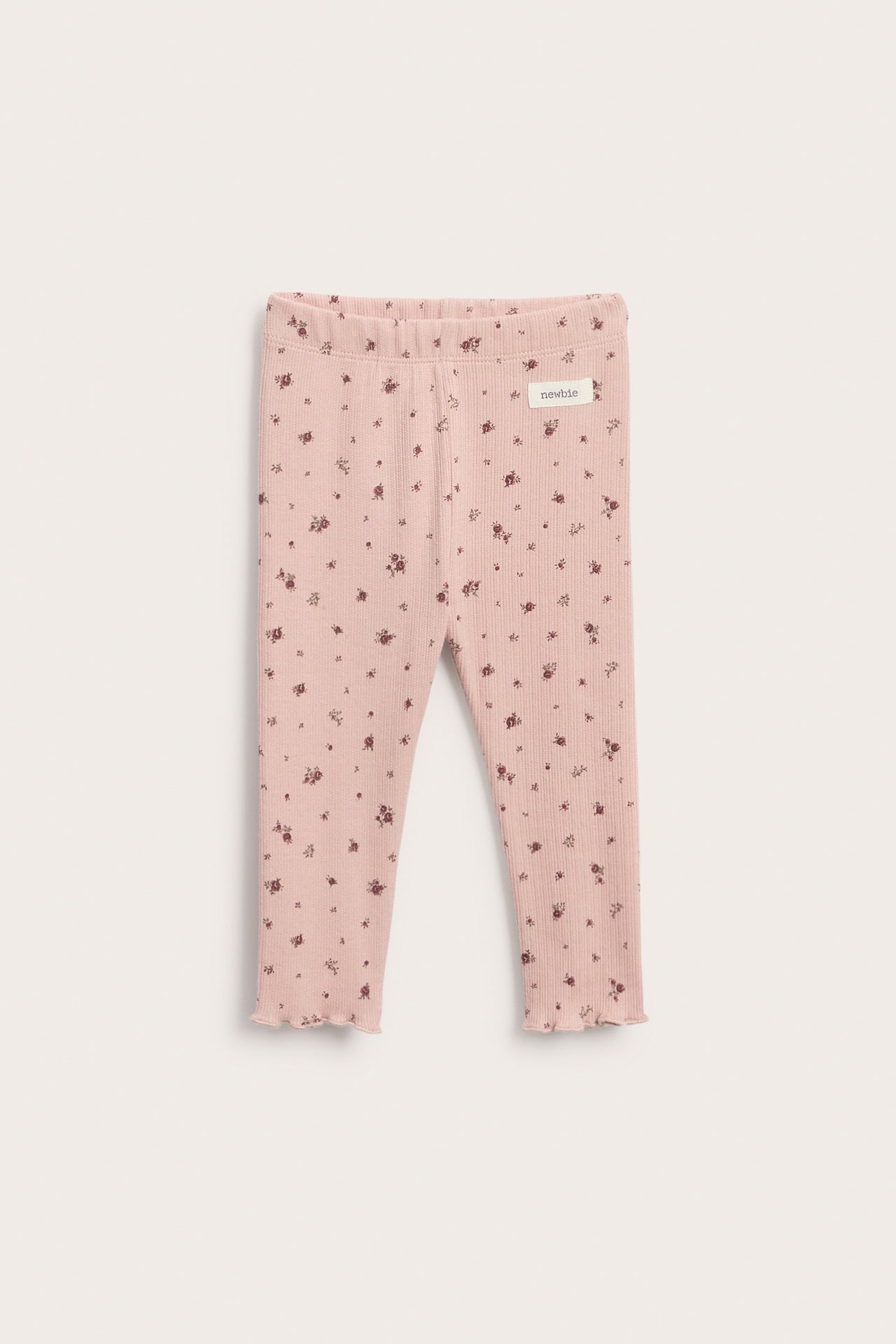 Vorderansicht gerippter rosa Baby-Leggings mit kleinem Blumenmuster und gewelltem Saum.