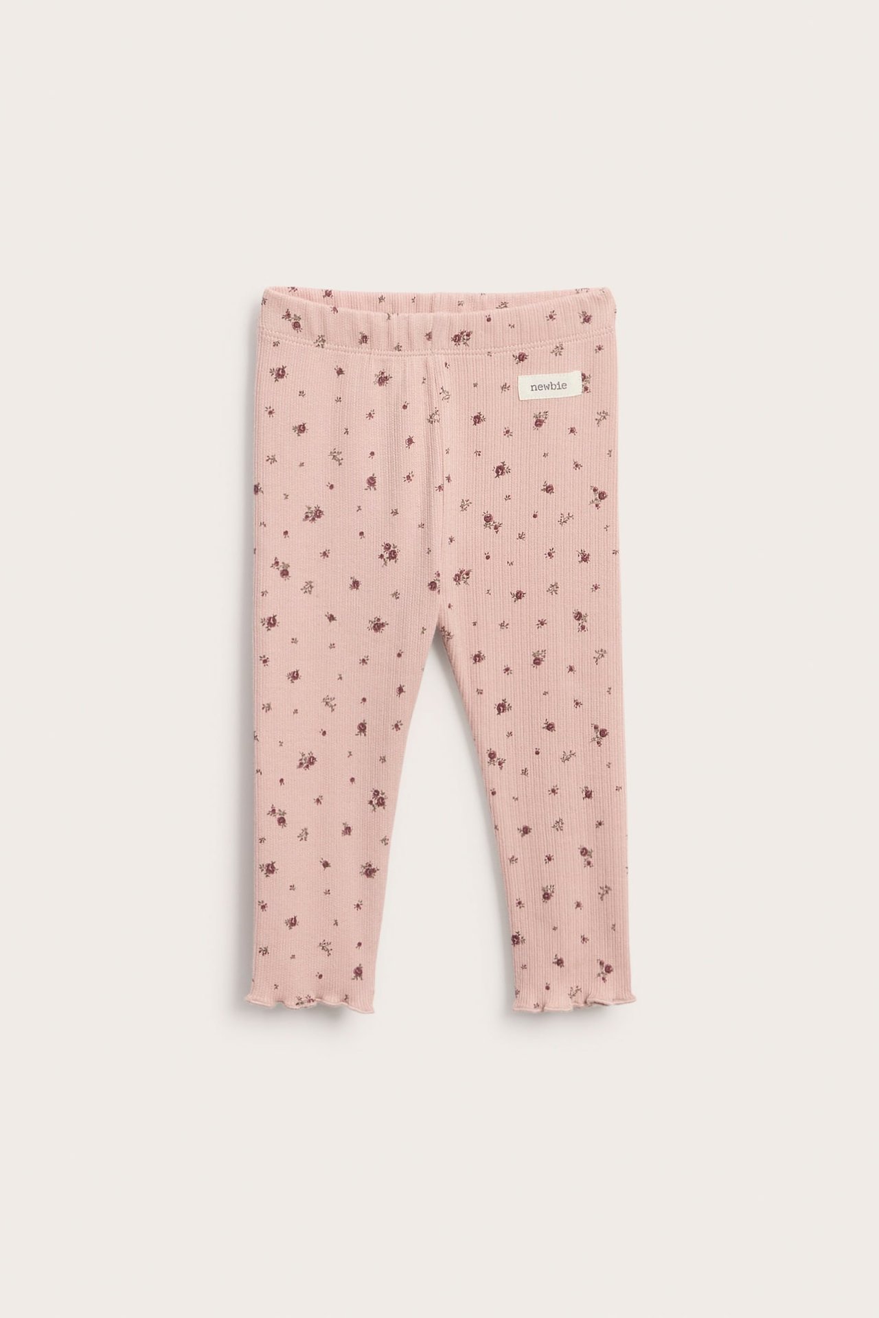 Vorderansicht gerippter rosa Baby-Leggings mit kleinem Blumenmuster und gewelltem Saum.