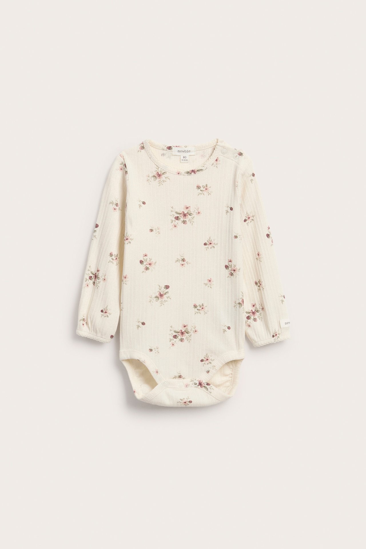 Front view of a baby's cream ribbed long-sleeve bodysuit with small pink floral print.