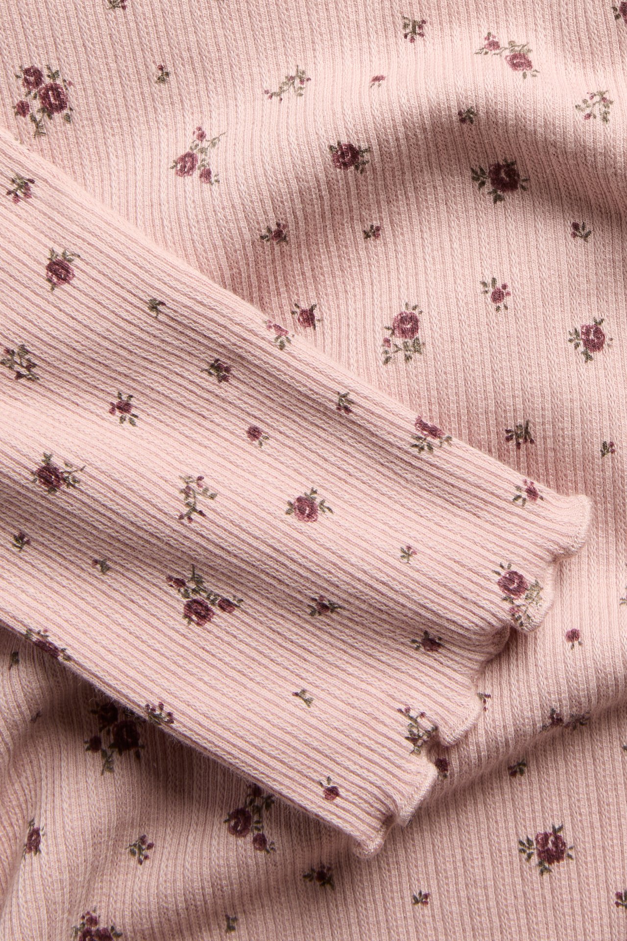 Close-up of a pink floral ribbed long-sleeve top with lettuce-edge trim.