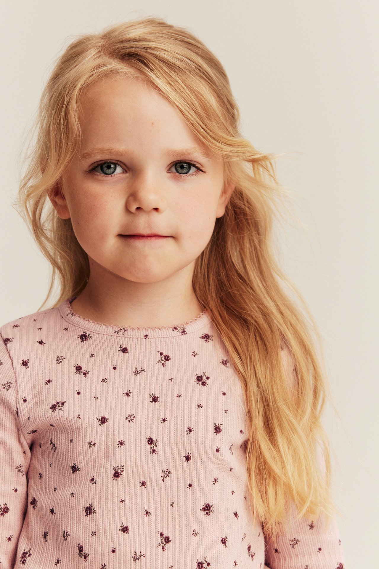 Vorderansicht Kind in hellrosa geripptem Langarmshirt mit kleinem Blumenmuster.