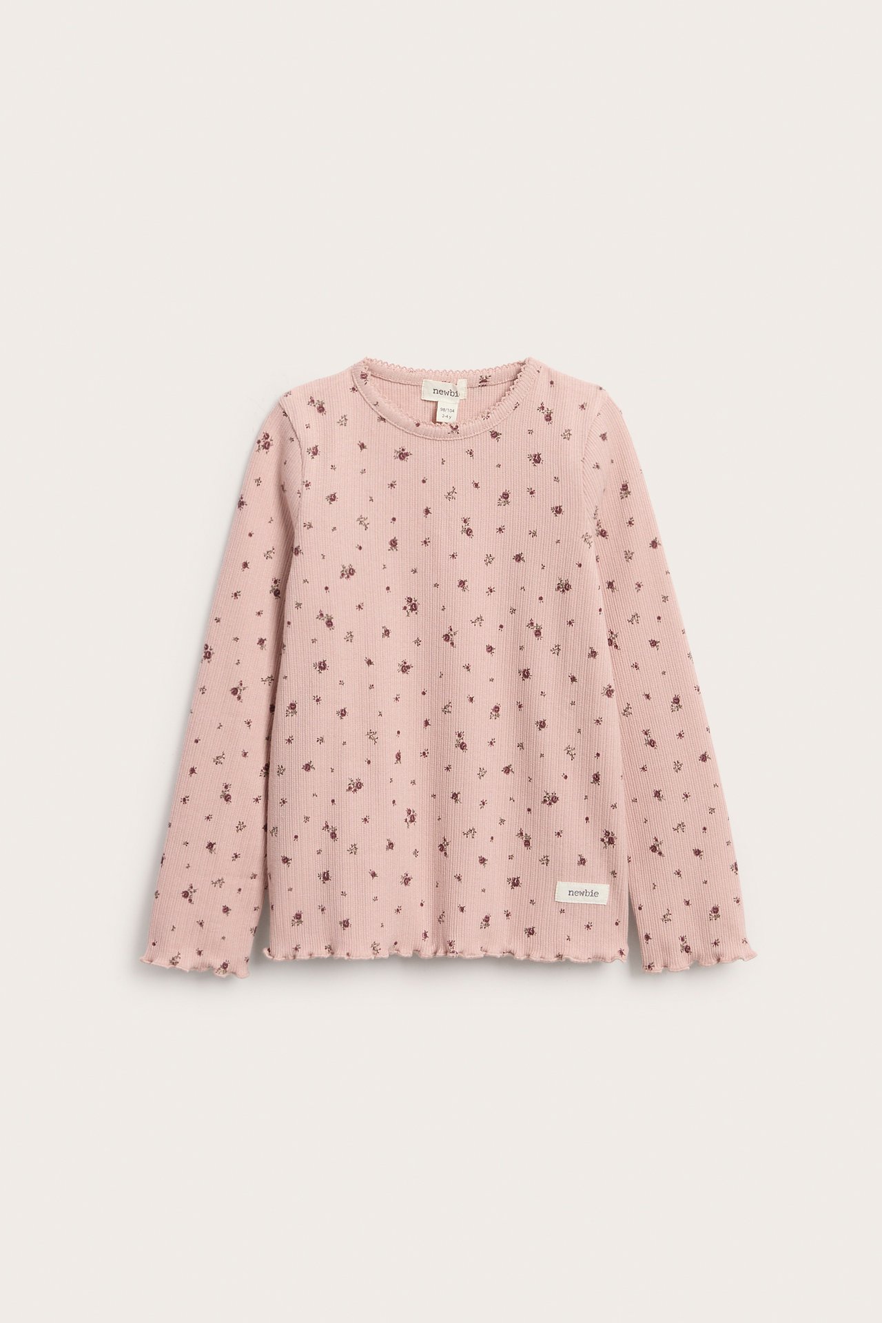 Vorderansicht eines rosa gerippten Langarmtops für Kinder mit Blumenmuster und Rüschensaum.