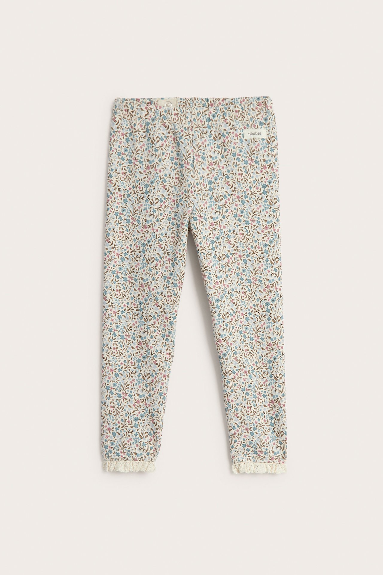 Vorderansicht von Baby-Leggings in Beige mit Blumenmuster und Rüschenspitze.